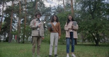 Kitapları tutan neşeli öğrencilerin yavaş çekim portresi gülümseyen ve parkta atlayan ve gülen. Pozitif duygu ve gençlik kavramı.