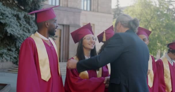 Гордый Профессор Поздравляет Группу Студентов Выпускных Шляпах Платьях Пределами Университета — стоковое видео