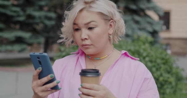 Neşeli Genç Asyalı Kadın Akıllı Telefon Tutarak Şehir Sokaklarında Kahveye — Stok video