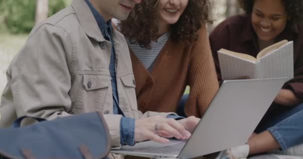 パークで屋外で学ぶインテリジェントな学生は ノートパソコンでブラウジングし 情報を議論する本を読む 青少年教育コンセプト — ストック動画
