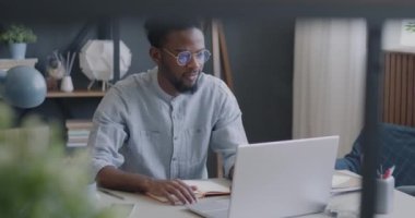 Modern apartmandaki masada bilgisayar kullanan Afrikalı Amerikalı bir işçinin portresi. Başarılı kişi ve serbest çalışan kavramı.
