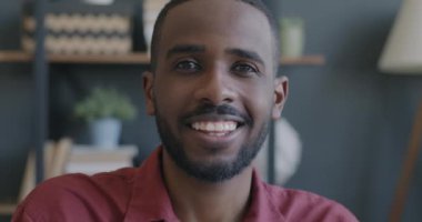 İş yerinde kameraya bakan gülümseyen Afrikalı Amerikalı adamın yavaş çekim portresi. Başarılı gençlik ve duygu ifadesi kavramı.