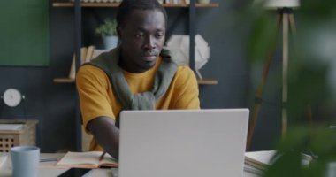 Genç Afrikalı Amerikalı girişimci bilgisayarını kullanıyor ve ofiste kahve içiyor. İş ve uzak iş yeri kavramı.