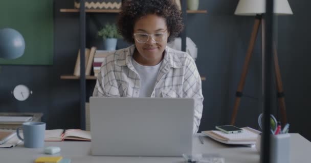 Kvinnelig Student Som Bruker Laptop Sjekker Smarttelefonmeldinger Som Sitter Ved – stockvideo