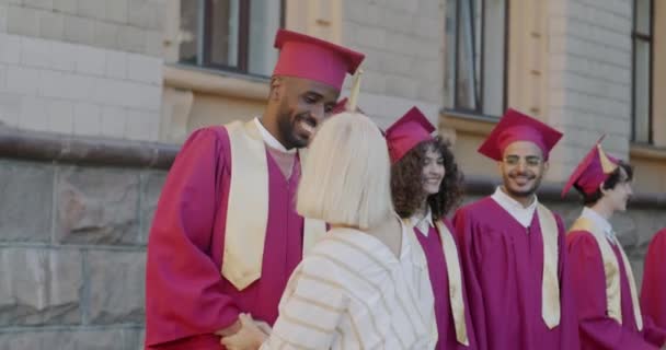 大学教授在大学校园里祝贺一群身穿礼服 头戴毕业帽的学生 成功的青年与教育概念 — 图库视频影像