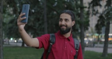 Neşeli Orta Doğulu bir adam akıllı telefon kamerasıyla selfie çekiyor ve şehirde iyi niyet gösterisi yapıyor. Fotoğraf ve insan konsepti.