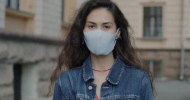 Surat maskesi takan Asyalı kadının yavaş çekim portresi Corona virüsü salgınında ayakta duruyor. Sağlık ve şehir hayatı kavramı.