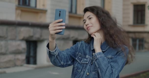 スマートフォンカメラにポーズする遊び心のあるアジアの女性のゆっくりとした動きの肖像画は 市街地で楽しんでいます 若者と写真コンセプト — ストック動画