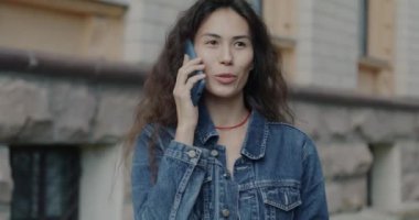 Cep telefonuyla konuşan kaygısız Asyalı kadın portresi şehirde dostça sohbetin keyfini çıkarıyor. Gençlik ve iletişim kavramı.