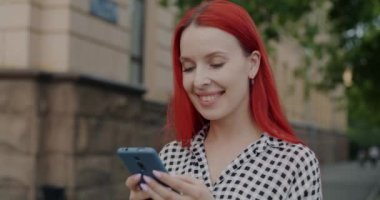 Çevrimiçi mesajlaşan duygusal genç kadın portresi dışarıda duran sohbete odaklanmış akıllı telefon mesajlarıyla. İnternet bağlantısı ve aygıt kavramı.