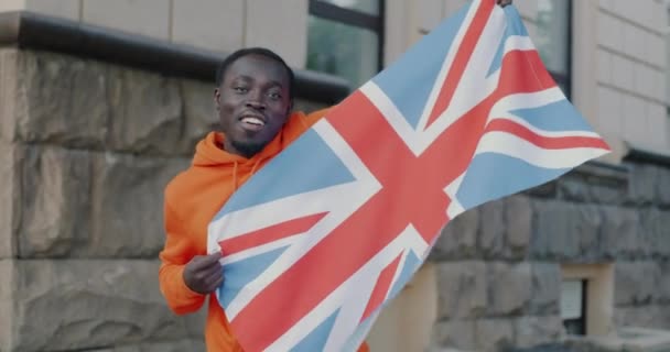 Медленный Портрет Радостного Афроамериканца Размахивающего Британским Национальным Флагом Стоящего Улице — стоковое видео