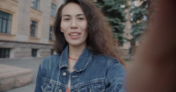 在城市街道上 一个快乐的亚洲女人一边说着一边看着相机在网上拍着视频 慢动作的肖像 交流与人的概念 — 图库视频影像