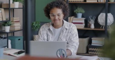 Bilgisayarla çalışan neşeli Afrikalı Amerikalı kız öğrenci evden online olarak çalışıyor. Eğitim ve modern teknoloji kavramı.