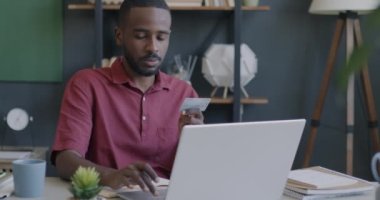 Başarılı girişimci Afrikalı Amerikalı adam elinde dizüstü bilgisayarla gülümsüyor ve ofiste mutlu oluyor. Bankacılık ve iş konsepti.