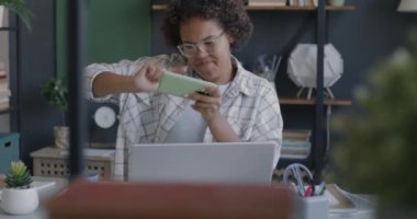 Ofisteki tatilde akıllı telefon kullanarak oyun oynayan neşeli bir çalışan. Modern teknoloji ve oyun aleti kavramı.