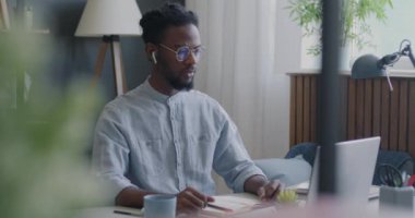 Hırslı serbest çalışan Afrikalı Amerikalı müşteriyle konuşuyor. Bilgisayarla video görüşmesi yapıyor ve evde yazıyor. İletişim ve iş birliği kavramı.