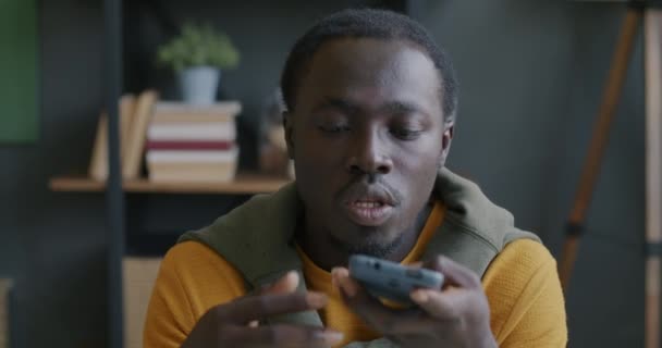アフリカ系アメリカ人男性が音声メッセージを録音し アパートの室内で音声チャットを聞く 人とコミュニケーションの概念 — ストック動画
