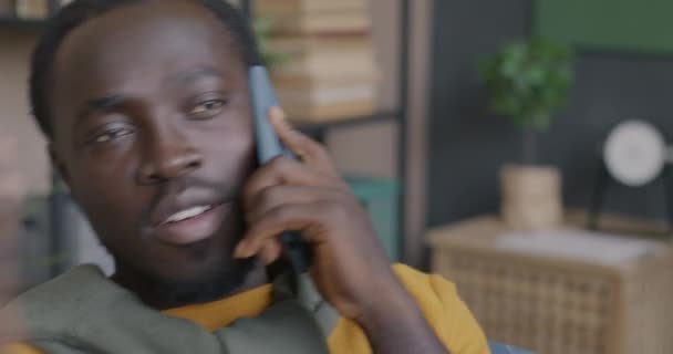 明るいアフリカ系アメリカ人男性のクローズアップ肖像画は 自宅で屋内で話す携帯電話を作っています コミュニケーションと現代技術のコンセプト — ストック動画