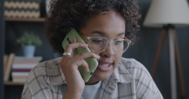 友好的なアフリカ系アメリカ人の女性が携帯電話で話し デスクでノートパソコンのタイピングを使用して描かれている ビジネスコミュニケーションとオフィスワークのコンセプト — ストック動画
