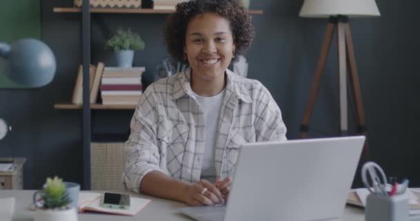 オフィスのコンピュータデスクに座って微笑んでいる陽気なアフリカ系アメリカ人の女性のゆっくりとした動きの肖像画 プロの職業とキャリアコンセプト — ストック動画