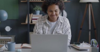 Ofiste yalnız çalışan, akıllı telefon ve laptop kullanan, kablosuz kulaklık takan genç bir kadın. Elektronik cihazlar ve iş konsepti.