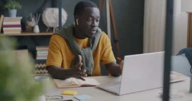 Öğrenci Afrikalı Afrikalı Amerikalı evde bilgisayar ve kablosuz kulaklıkla yazıp konuşuyor. Eğitim ve modern teknoloji kavramı.