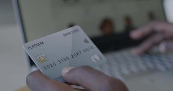 クレジットカードを持っている男性の手のクローズアップとデスクでラップトップコンピュータとタイピング バンキングと現代金融技術のコンセプト — ストック動画