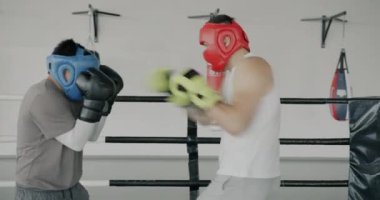 Spor salonunda antrenman yapan iki genç boksör kask ve eldiven takarak boks antrenmanı yapıyor. İnsanlar ve dövüş sanatları konsepti.