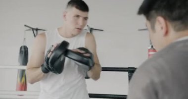 Kafkas boks koçu Asyalı sporculara modern spor salonunda birlikte eğitim veriyor. Spor merkezi aktivitesi ve antrenör konseptiyle çalışma.