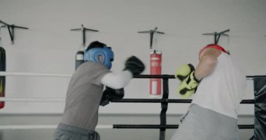 Genç boksörlerin antrenman yaparken yavaş hareket etmesi spor salonunda kask ve eldiven takarak yumruk atması.
