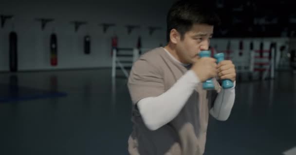 一名身穿运动服的年轻亚洲男子举着哑铃抛掷拳的画像 训练拳击在体育馆里进行 积极的生活方式和体育概念 — 图库视频影像