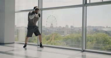 Asyalı bir adamın spor salonunda kulaklık takıp panoramik arka planda müzik dinlemesi. Halk ve spor konsepti.