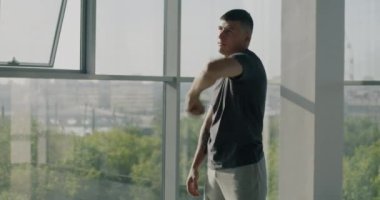 Hafif kentsel spor salonunda egzersiz yapan genç kaslı adamın portresi kolları ısıtma eğitimine odaklandı. Aktif yaşam tarzı ve refah kavramı.