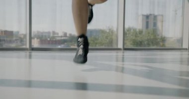 Spor hocası spor salonunda kardiyo egzersizi yaparken spor ayakkabılarıyla atlayan erkek bacaklarının yakın çekimi. Aktif yaşam tarzı ve eğlence konsepti.