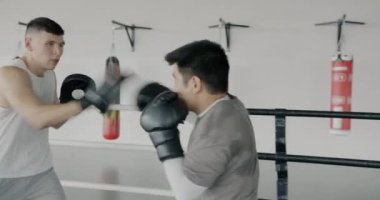 Modern spor salonunda antrenman yapan iki beyaz ve Asyalı ringde antrenman yapmaya odaklanmış. Aktif yaşam tarzı ve spor merkezi kavramı.