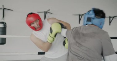 Genç sporcu boksörler modern spor salonunda vücut koruması için eldiven ve kask takarak antrenman yapıyorlar. Boks ve egzersiz kavramı.