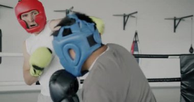 Spor salonunda kask ve eldiven takarak birlikte antrenman yapan genç erkeklerin yavaş çekimleri. Profesyonel spor ve dövüş sanatları konsepti.