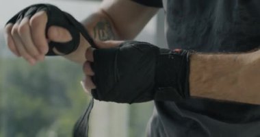 Spor salonunda spor antrenmanı yaparken, boks maçına hazırlanan kayışlarla sarılı erkek ellerinin yakın çekimi. Aktif yaşam tarzı ve dövüş sanatları konsepti.