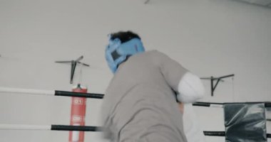 Profesyonel boksörler, kask takan ve eldiven takan erkekler modern spor salonunda antrenman yapıyor, yumruklarını dövüşlere yoğunlaştırıyor. İnsanlar ve dövüş sanatları konsepti.