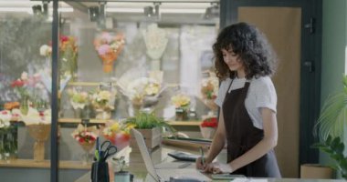Çiçekçi genç adam iş yerinde kahkahalar atan bayan meslektaşına kahve götürmeye gitti. İçeceği ve perakende konseptini çıkar..