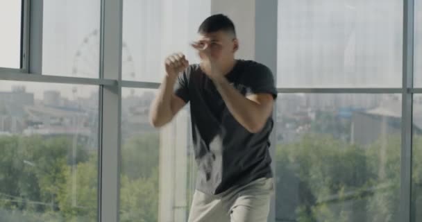 軽いガラス壁のジムでボクシングの動きを実践する魅力的な若いスポーツマントレーニングアームのスローモーション 人とスポーツのコンセプト — ストック動画