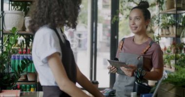 Orta Doğulu kadın çiçekçi müdürü mağazada birlikte duran bayan meslektaşla konuşuyor. İş ve satış mesleği kavramı.