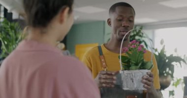 Afro-Amerikalı satıcı bayan müşteriyle çiçekçide çiçek açma konusunu konuşuyor. Perakende ve başarılı çiçekçilik konsepti.