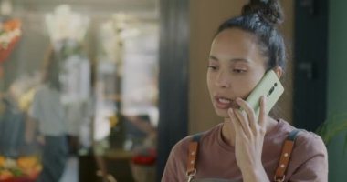 Çiçekçi işletme müdürü cep telefonuyla müşteriyle konuşuyor. Kapalı mekandaki aramalara cevap veriyor. İletişim ve başarılı perakende konsepti.