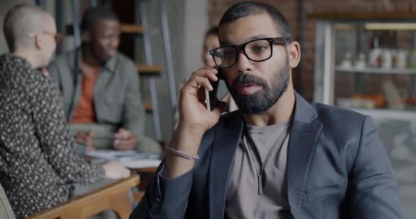 Ближневосточный Бизнесмен Говорит Мобильному Телефону Трогает Очки Сидя Кафе Коммуникация — стоковое видео