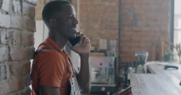 Молодой Афроамериканец Бариста Разговаривает Мобильному Телефону Стоя Стойкой Кафе Работник — стоковое видео