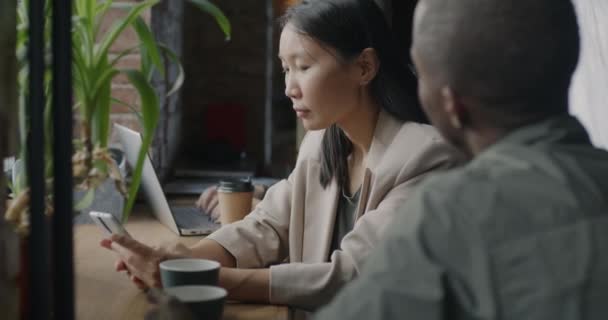 亚洲女商人使用智能手机 然后在合作空间与男同事非裔美国人交谈 人与通信概念 — 图库视频影像