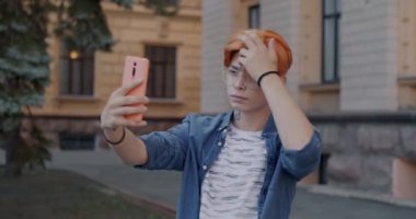 Akıllı telefon kamerasına poz veren, özçekim yapan ve şehirde eğlenen kaygısız Asyalı adam. İnsanlar ve fotoğraf konsepti.