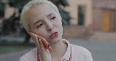 Cep telefonunda sohbet eden mutlu sarışın kız açık şehir geçmişine gülüyor. İnsanlar ve cep telefonu iletişim kavramı.