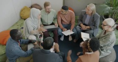 İş adamlarının çok uluslu gruplar halinde konuştuklarını ve yaratıcı ofiste dizüstü bilgisayarla çalıştıklarını görüyoruz. İş iletişimi ve insan kavramı.